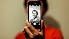 Person holding phone displaying black and white smiling face photo
