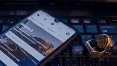 Smartphone on keyboard displaying digital wallet app near crypto coins