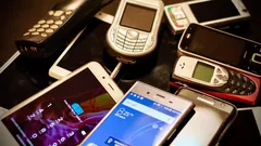Collection of various old and new mobile phones and tablets piled together