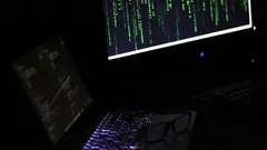Dark room with laptop and monitor displaying green and white code