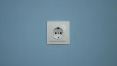 White electrical outlet on blue wall ready for plug connection