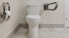 Modern accessible bathroom with white toilet and stainless steel grab bars